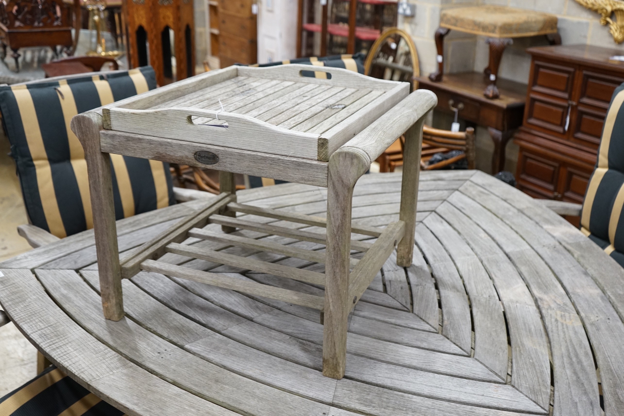 A Hartman weathered teak triangular garden table, width 170cm, height 76cm, six folding armchairs with seat pads and a tray top side table.